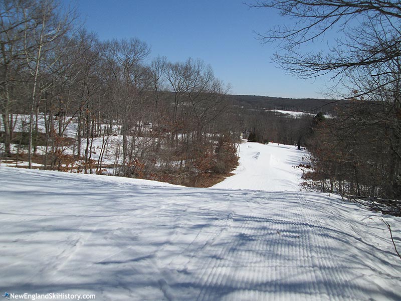 A winter sports scene at Yawgoo Valley, Rhode Island, featuring a ski resort amidst beautiful winter scenery, with a skier navigating the snow-covered slopes.
