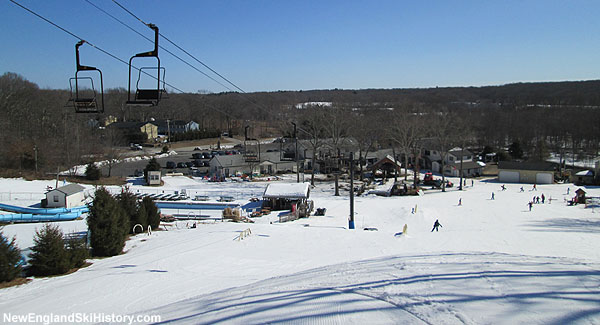 A winter sports scene at Yawgoo Valley Rhode Island showcasing a bustling ski resort with a ski lift in operation amid snow-covered hills.