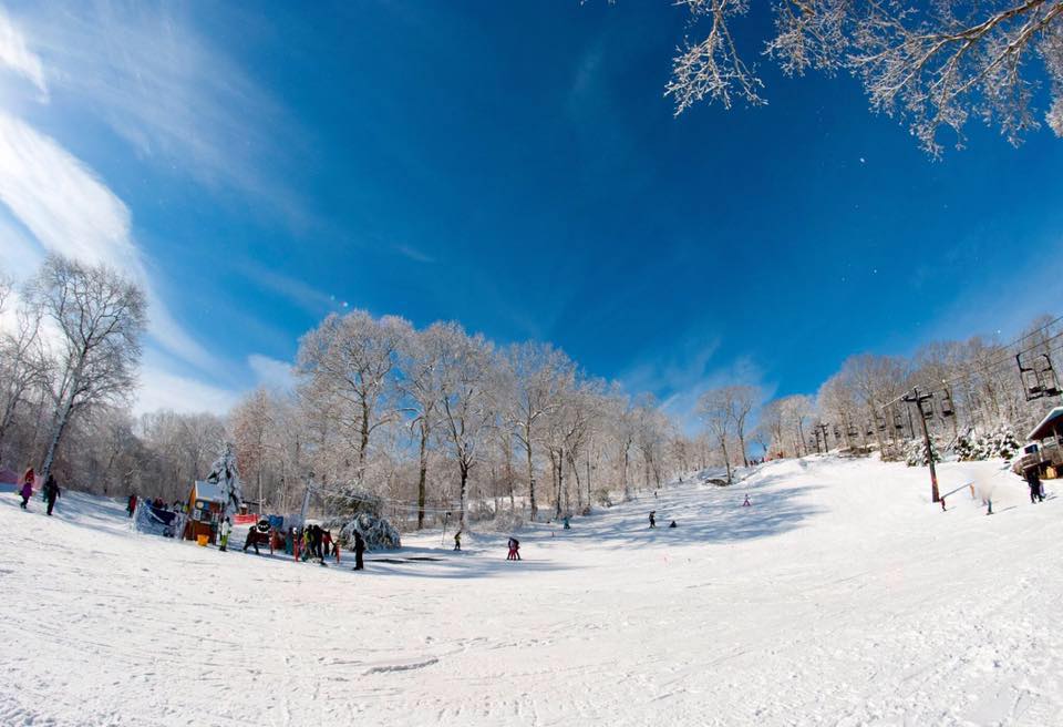Winter scene at Yawgoo Valley, Rhode Island, featuring a bustling ski resort surrounded by a stunning snowy landscape with a charming chalet in view.
