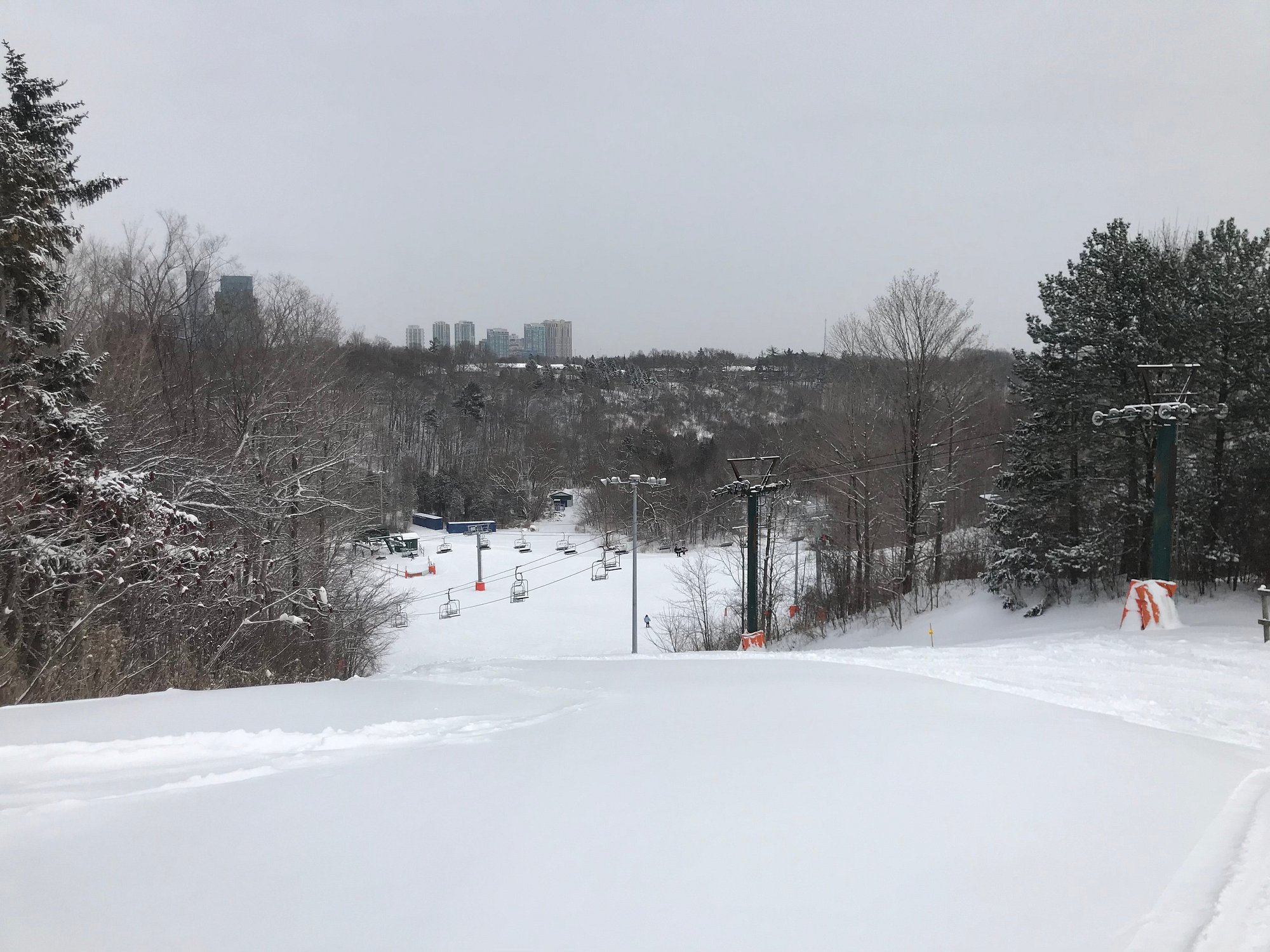 Winter scene at Earl Bales, North York in Ontario, Canada featuring a bustling ski resort with enthusiasts engaged in winter sports amidst stunning snowy scenery.