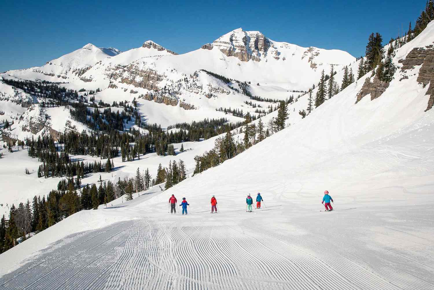 Jackson Hole in USA - a group of people skiing down a snow covered mountain.
