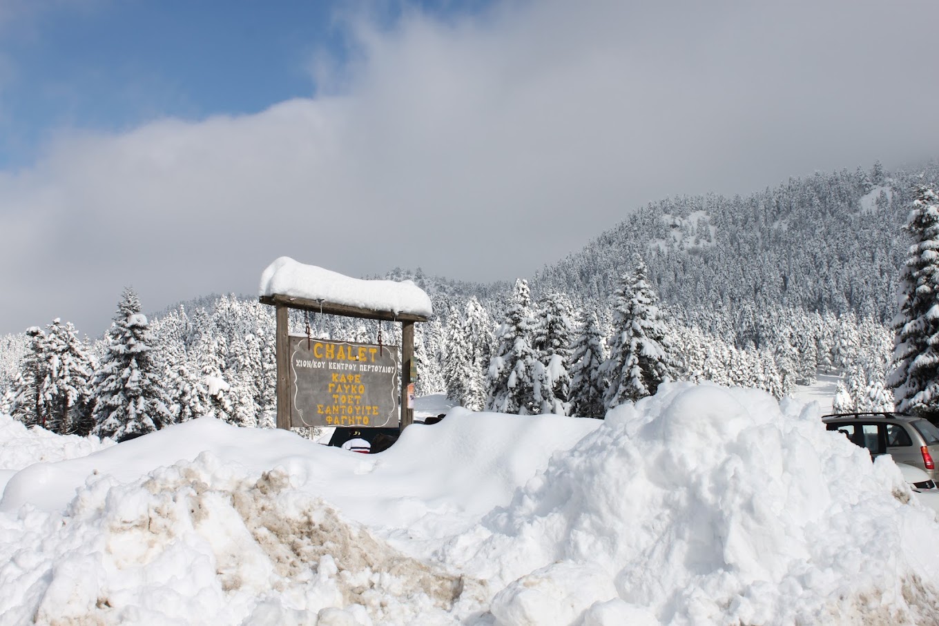 Koziakas – Pertouli in Greece - a truck is parked in the snow near a sign.