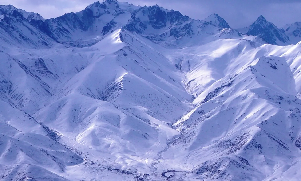 Norus in Kyrgyzstan - a large mountain covered in snow under a cloudy sky.