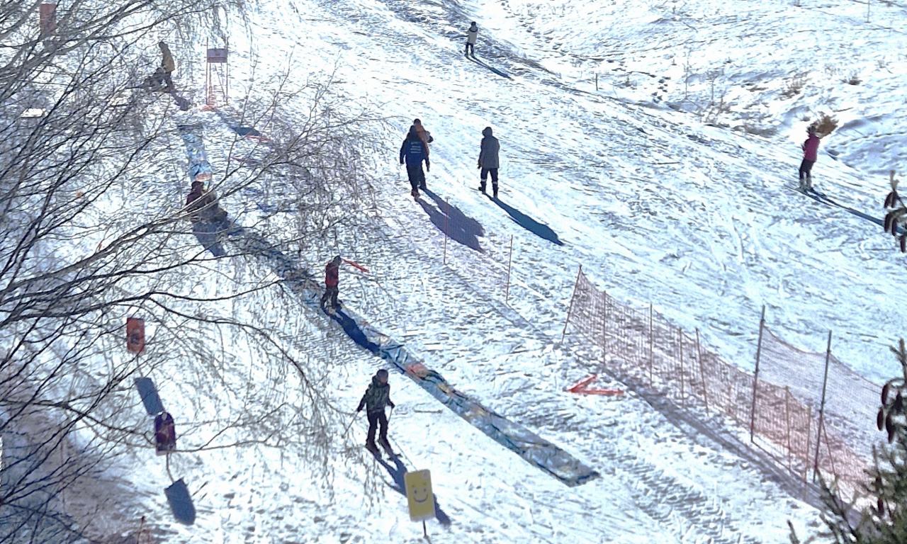 Norus in Kyrgyzstan - a group of people are skiing down a hill.