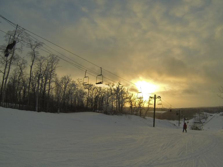 View of a lively winter sports scene at Bottineau Winter Park in North Dakota USA featuring a ski lift an active skier and a cozy chalet amidst a bustling ski resort.