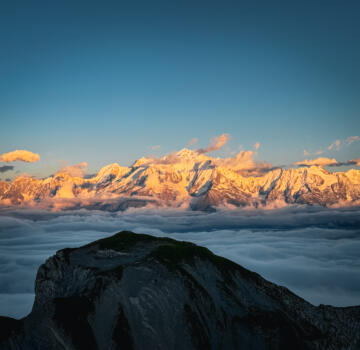 View of a snowy mountain in La Clusaz | Manigod France punctuated by a quaint chalet under a clear sky. The scene encapsulates the beauty and thrill of winter sports.