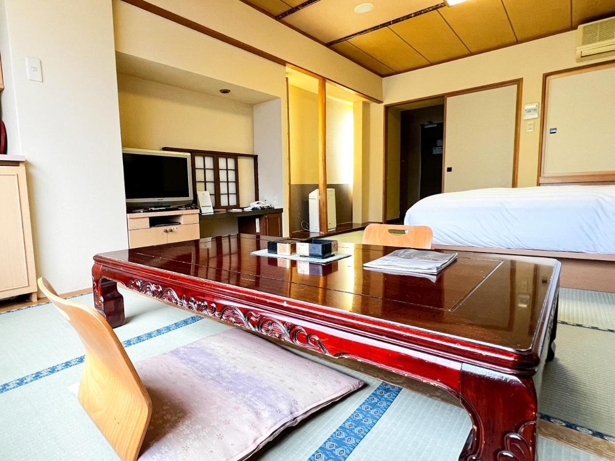 Kokusetsu Akankohan in Japan - a room with a bed, desk and tv.