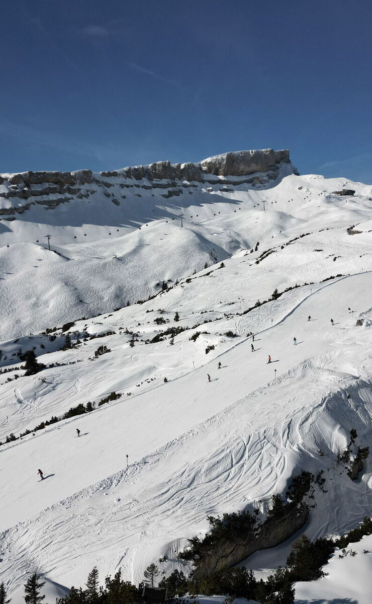 Ifen in Austria - a group of people skiing down a snowy mountain.