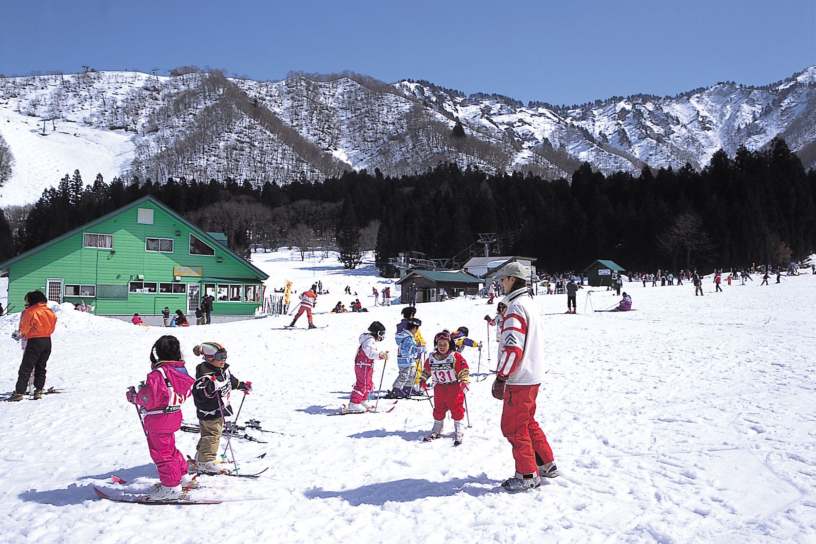 Nakazato Snow Wood in Japan - a group of people skiing down a snow covered hill.