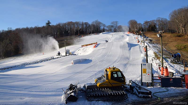 Winter scene at Woodbury, Connecticut, featuring snow-covered slopes with a busy ski resort and a charming challet, indicative of a lively winter sports centre.