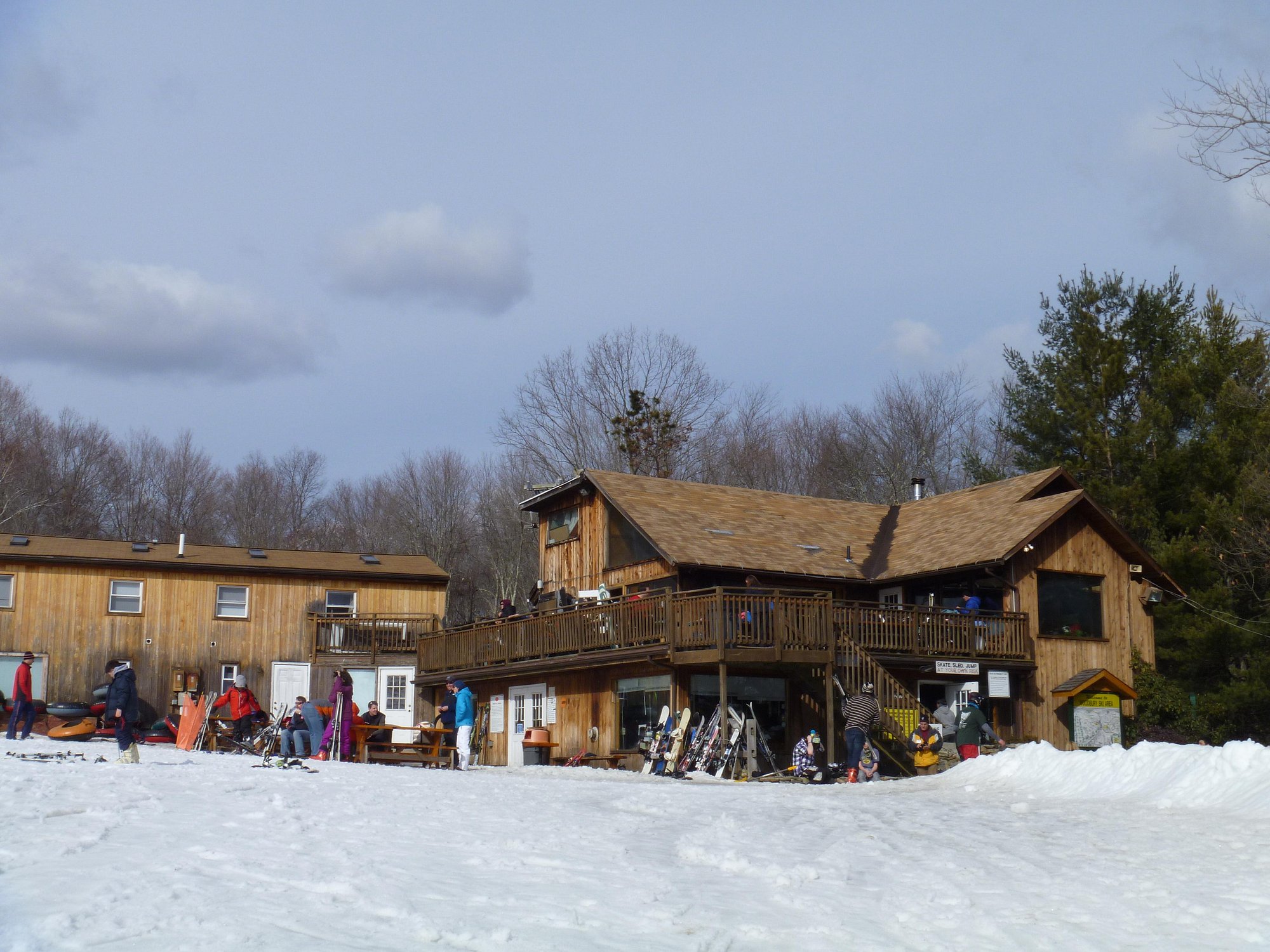 A winter scene at a ski resort in Woodbury Connecticut featuring various winter sports activities a ski lift and a chalet.