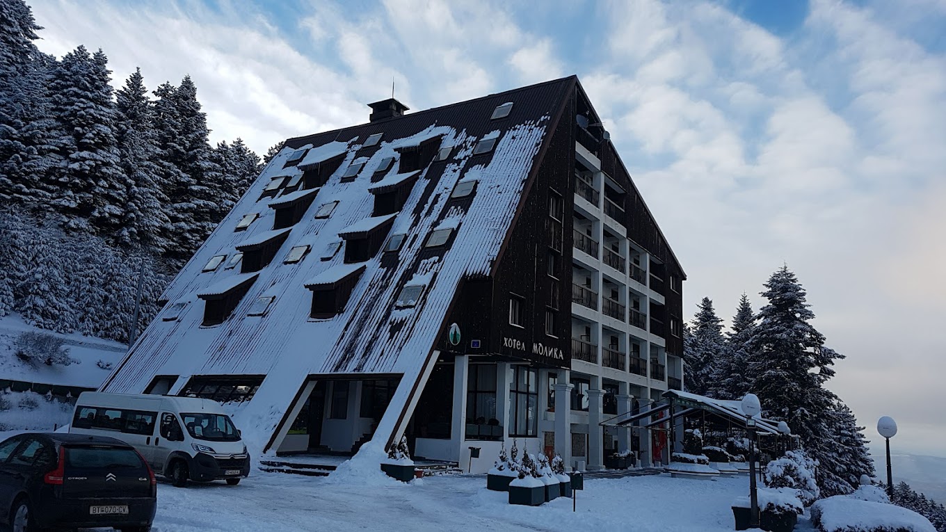 Kopanki in North Macedonia: a building covered in snow with cars parked in front.