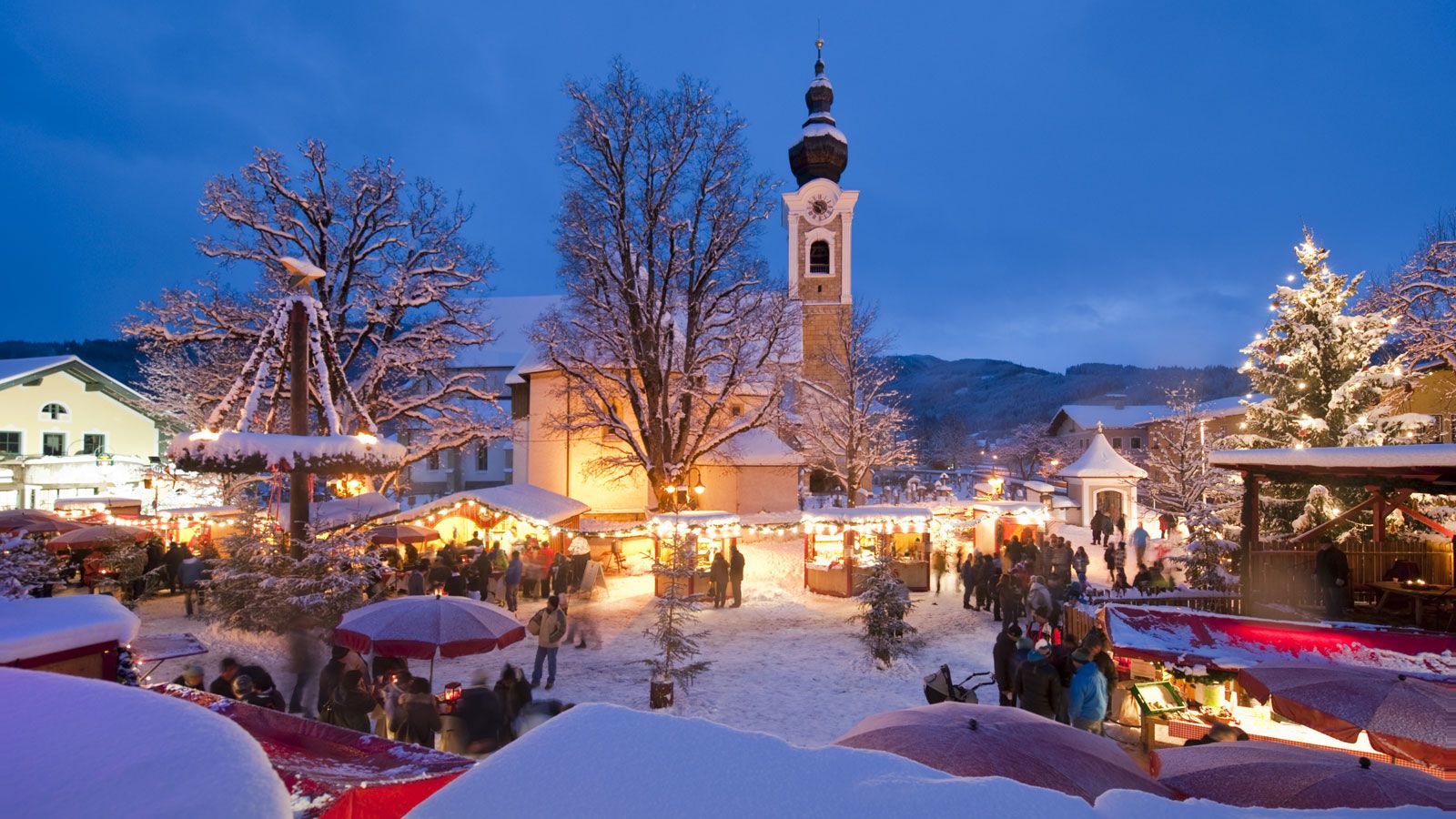 Salzbuger Sportwelt -Amade in Austria - a snowy village with christmas lights and a clock tower.