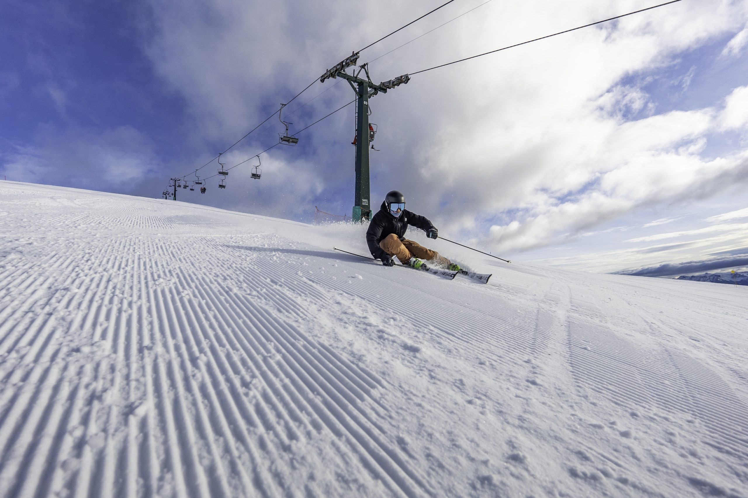 A skier is enjoying the winter sports scene at Catedral Alta Patagonia in Argentina. The ski lift and chalet add to the ambiance of this popular snowboarding destination.