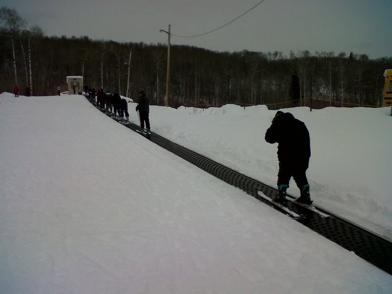 A skier enjoying winter sports at Duck Mountain – Kamsack Saskatchewan with a ski lift visible in the background of the snowy ski resort.