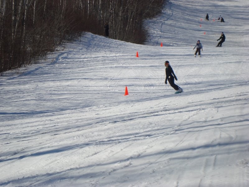 A skier navigating a snowy trail at Duck Mountain in Kamsack, Saskatchewan, part of a bustling winter sports centre complete with a ski lift and resort.