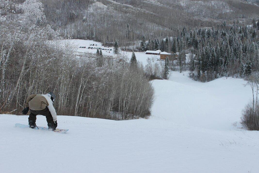 A snowboarder carving through fresh powder at Duck Mountain in Kamsack Saskatchewan Canada. The serene snow-covered landscape accentuates their daring ride.
