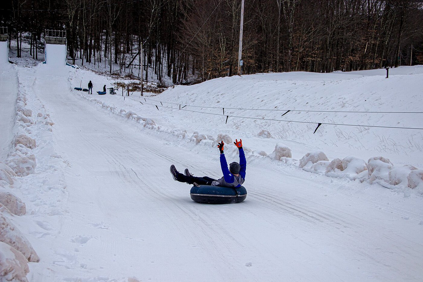 A snowy scene in Villa Roma The Catskills with a snowmobile parked near a chalet. Skiers participate in winter sports nearby making the location a bustling winter sports centre.