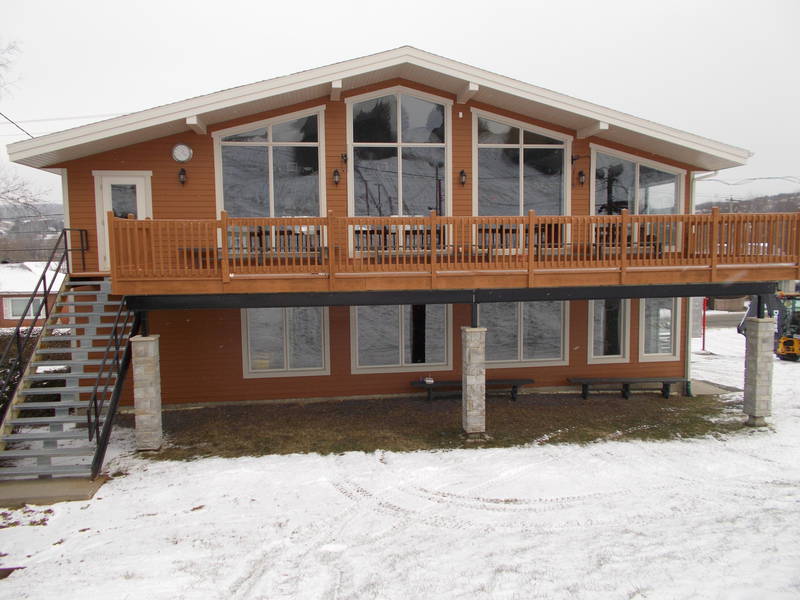 A cozy lodge and chalet nestled in a winter sports center at Beauce – Vallée-Jonction Quebec. This ski resort also features a distant mountain hut all painted in a serene snowy landscape.