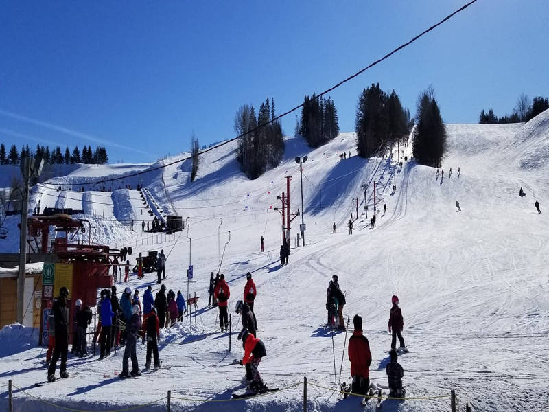 Winter sports scene at Beauce – Vallée-Jonction in Quebec, showcasing a bustling ski resort, complete with a ski lift, challet, and snow-dusted slopes.