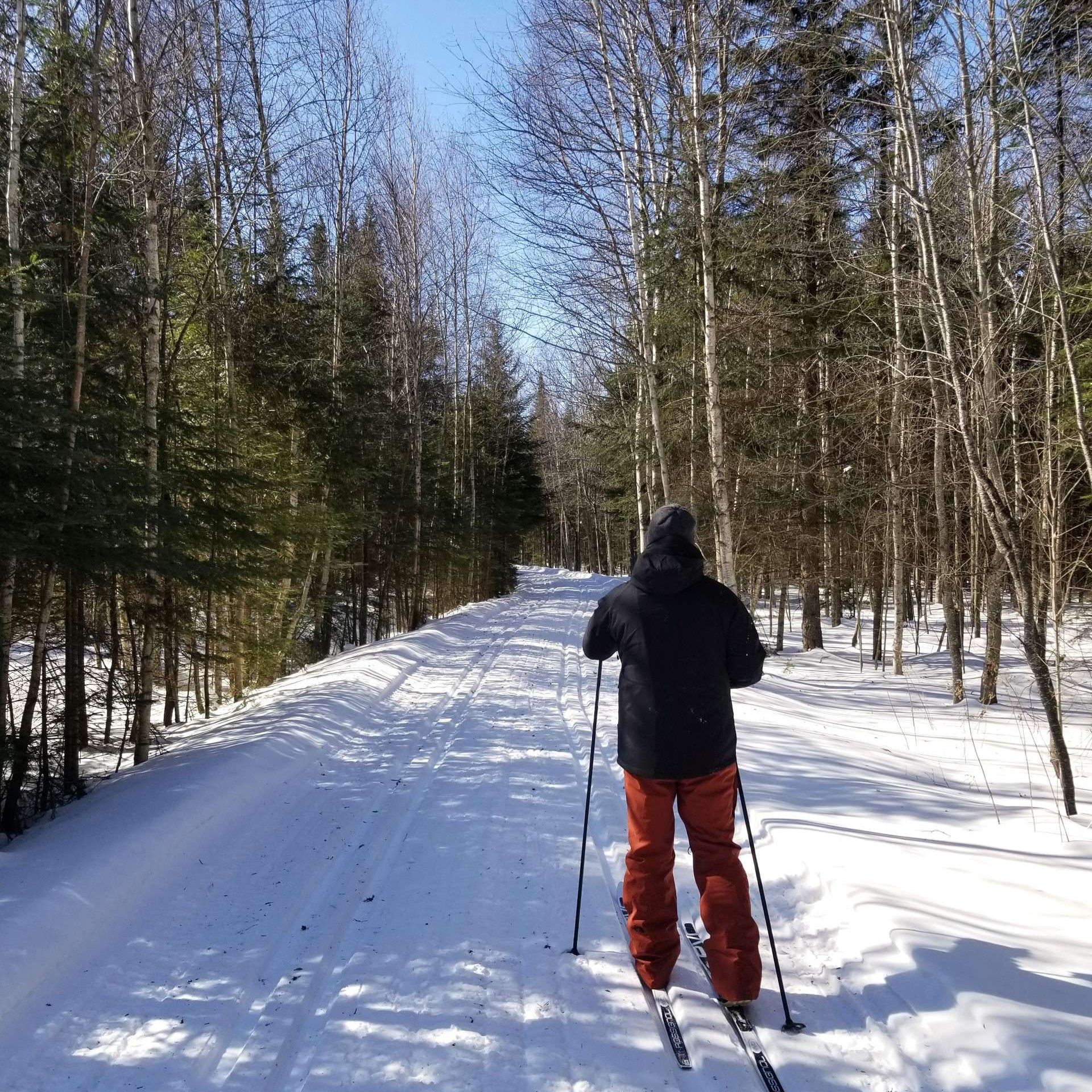 A skier enjoying a winter sports scene in Beauce – Vallée-Jonction Quebec with a chalet and a ski lift visible in the distance.