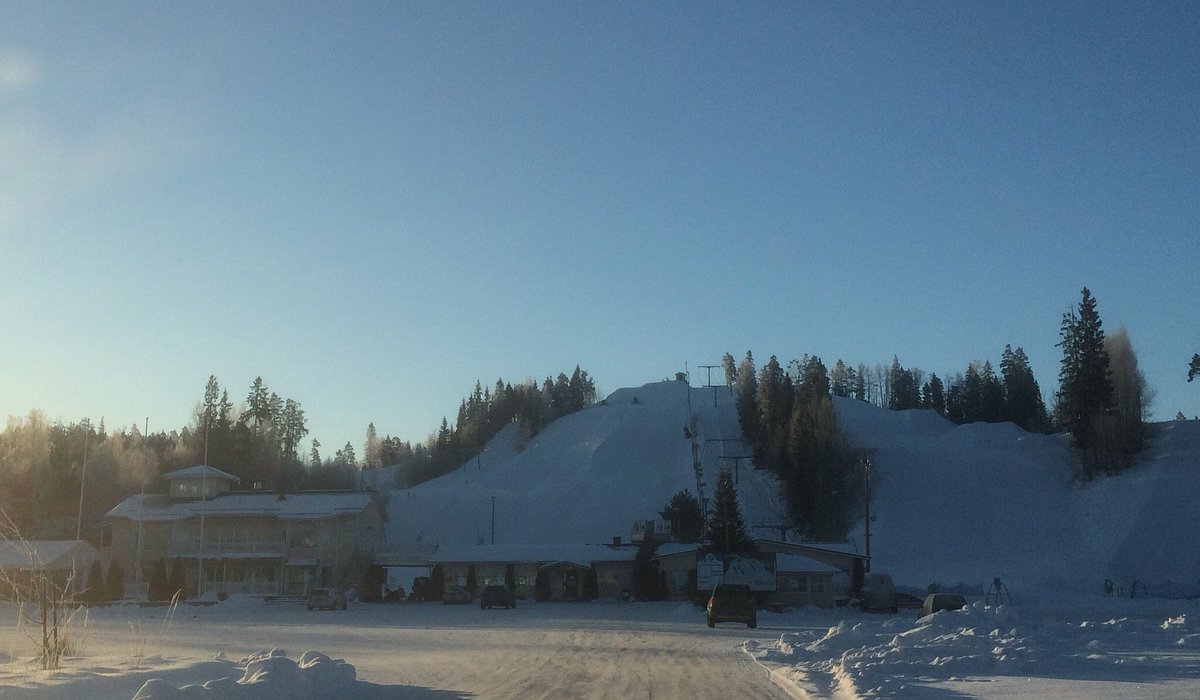 Vihti Ski Center in Finland - the sun is shining in the sky over a snow covered road.