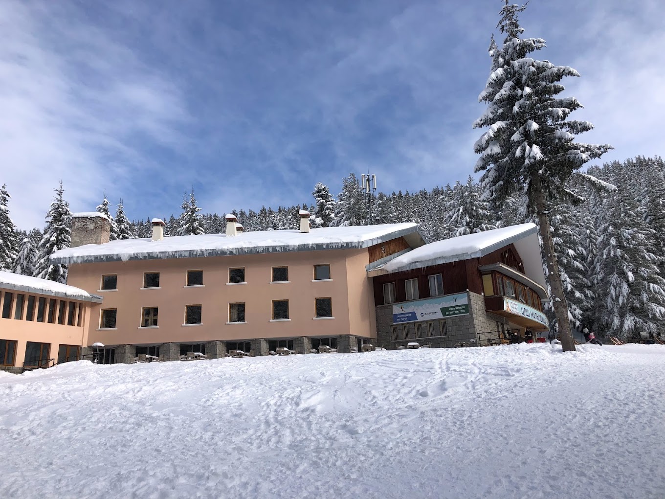 Malyovitsa in Bulgaria - a house covered in snow with trees in the background.