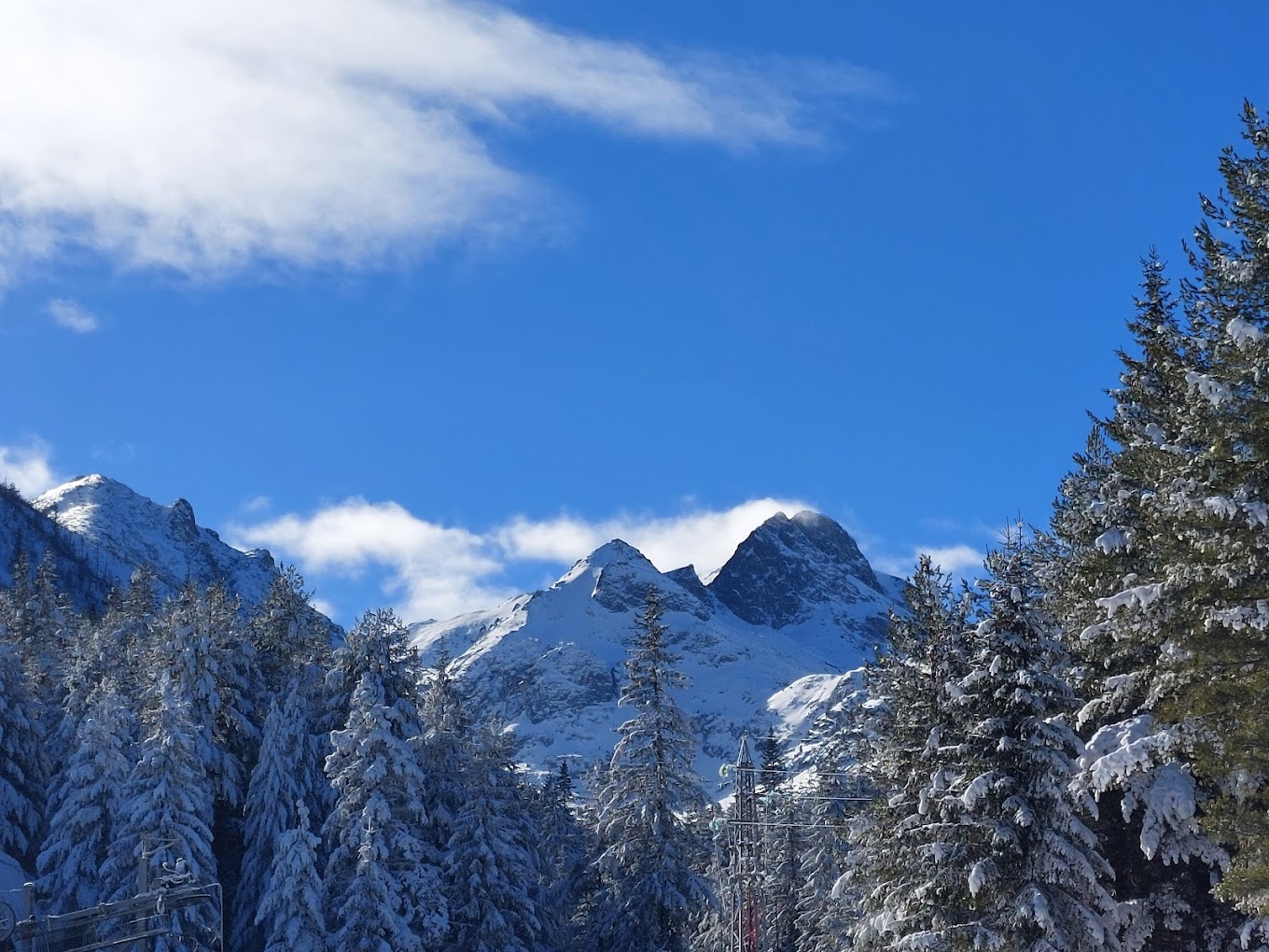 Malyovitsa in Bulgaria - snow covered trees and mountains against a blue sky.