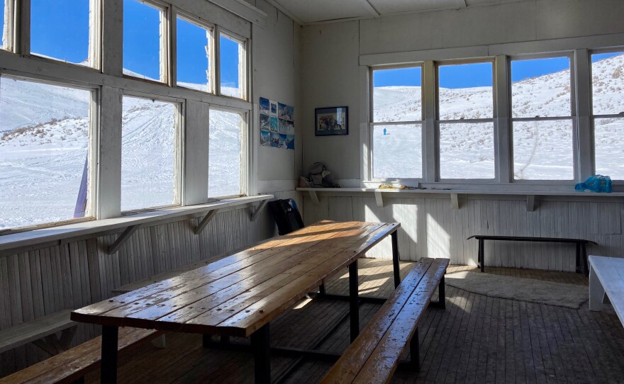 Winter sports scene at Blizzard Mountain in Idaho, showcasing a busy sports centre amidst a stunning display of winter scenery, complete with a cozy mountain hut.