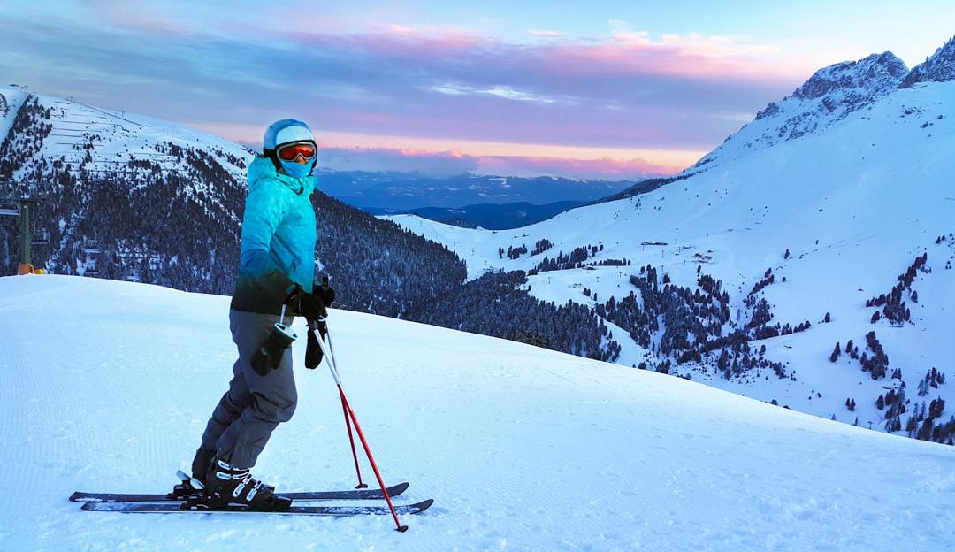 A skier dominating a winter sports scene at Sunrise Park, Arizona. Backdrop boasts a picturesque ski resort with a charming chalet. A snowboarder can be seen in the distance.