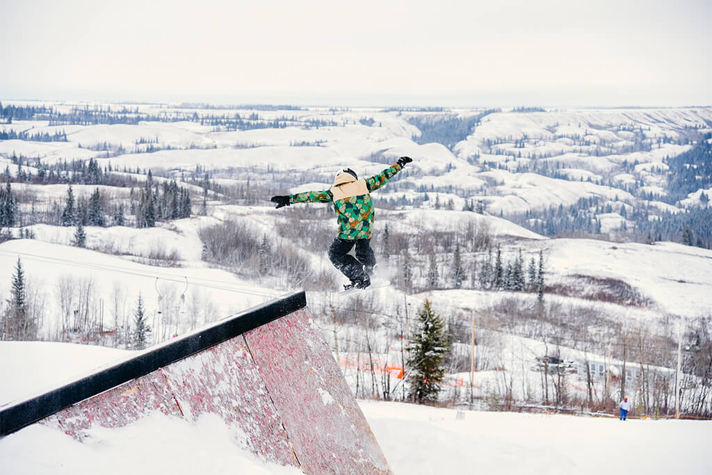 A snowboarder enjoying a sunny day on Fairview Ski Hill in Northern Alberta Canada showcasing the perfect balance between action and tranquility.