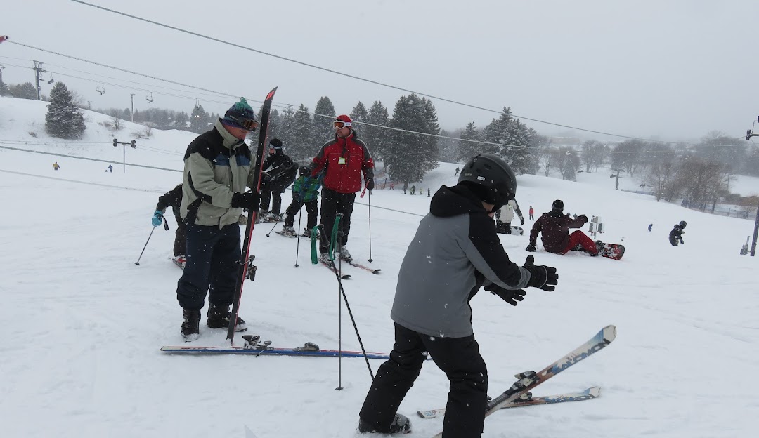 Winter sports scene at Villa Olivia in Bartlett, Illinois. A skier and a group of people enjoy skiing. There's a ski lift nearby and a family taking part in the activity.