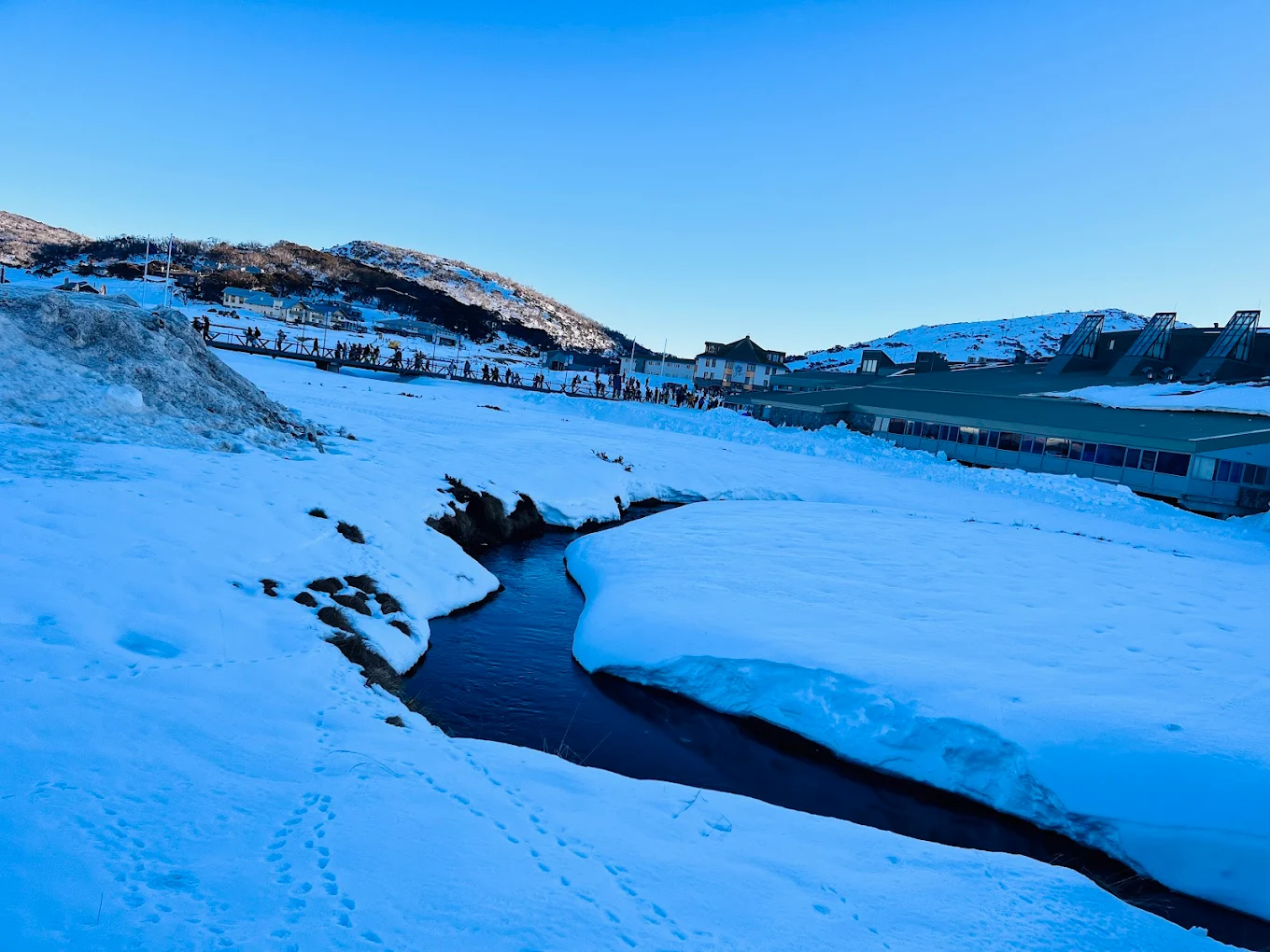 Perisher in Australia - a small stream in the middle of a snowy landscape.