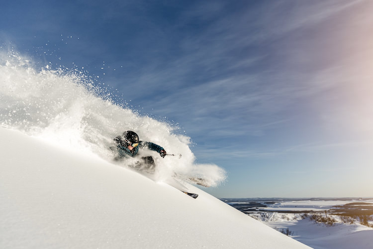 A skier and a snowboarder enjoying their winter sports at Dundret Lapland a ski resort in Gällivare Northern Sweden amidst the snow-covered landscape with the presence of a snowmobile nearby.
