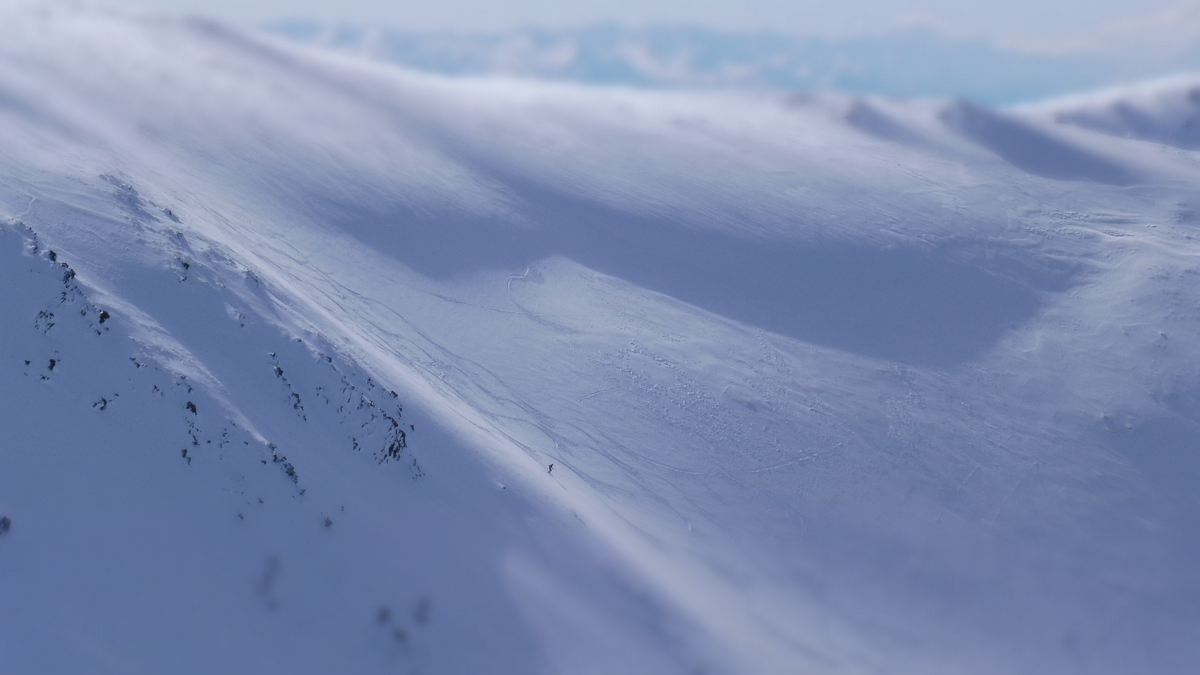 A skier enjoying a day on the snow-covered slopes at a ski resort in Awakino, New Zealand. Majestic mountains blanketed in snow serve as a picturesque backdrop.