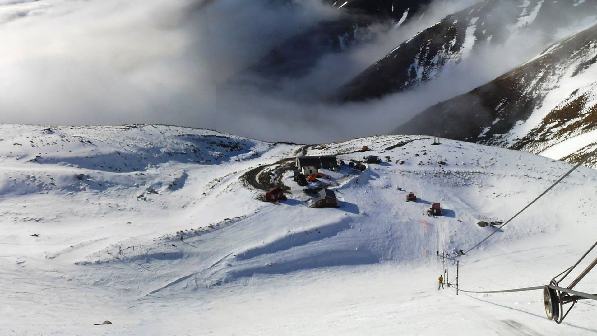 View of Awakino ski resort in Canterbury, New Zealand, highlighted by chalets against the backdrop of snow-covered slopes, depicting a vibrant winter sports scene.
