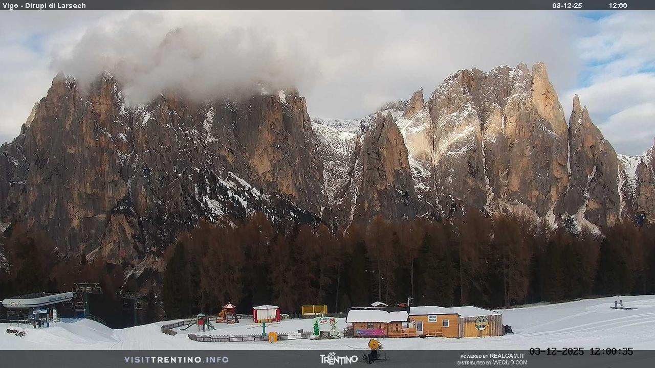 Catinaccio Ciampedie in Italy - the mountains are covered with clouds and trees.