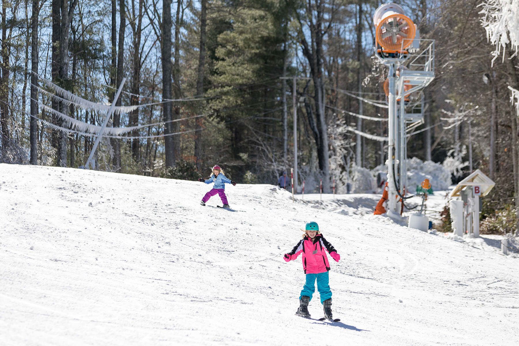 A lively winter sports scene at Sapphire Valley, North Carolina, featuring a skier gliding down a snowy slope by a ski lift, with a backdrop of a bustling ski resort.