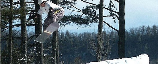 A snowboarder enjoying a winter day in Sapphire Valley, North Carolina, gliding down the snowy hillside gracefully with agility and speed.