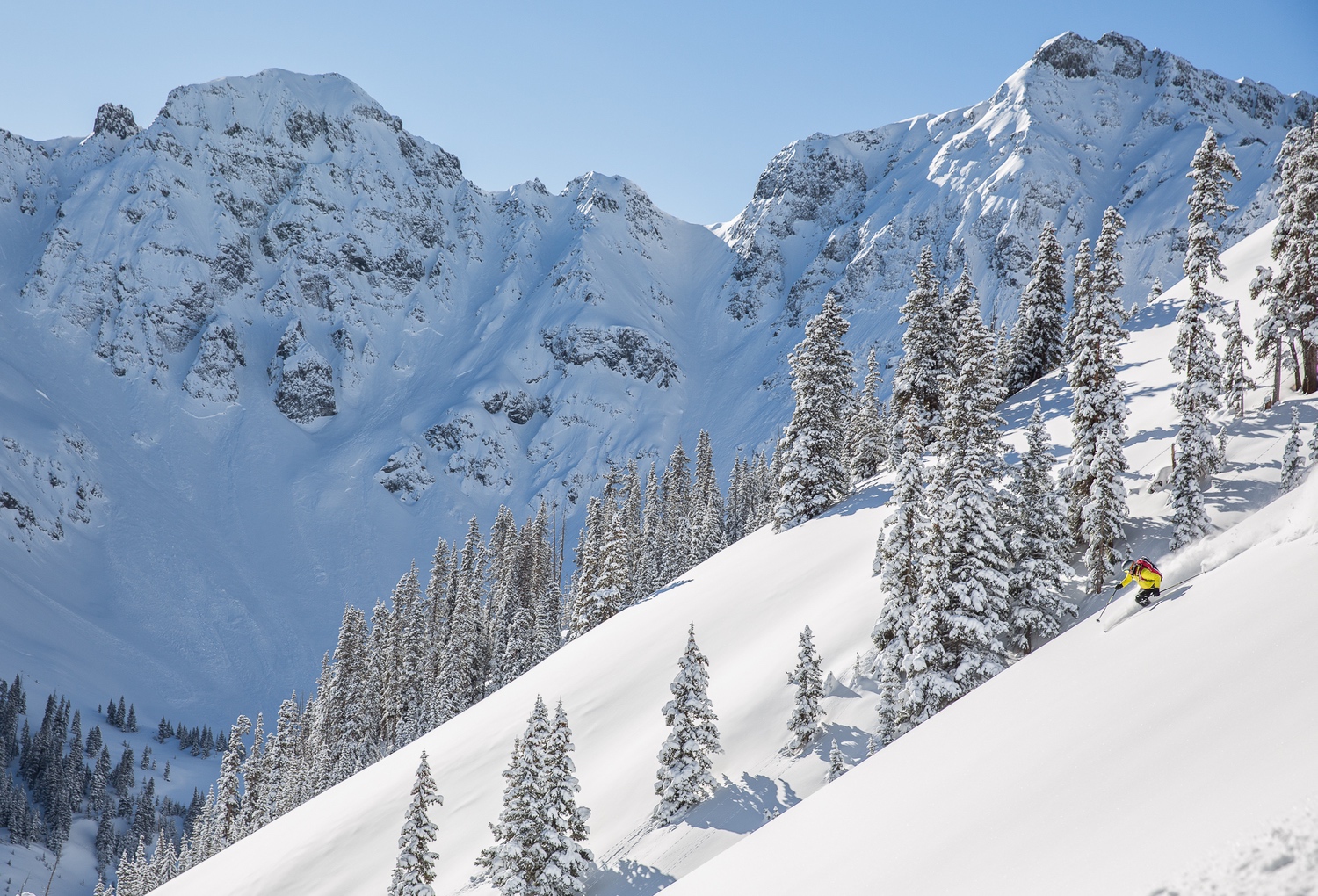 Silverton Mountain in USA - a man riding a snowboard down a snow covered mountain.