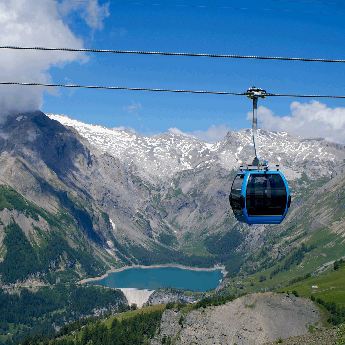 Crans Montana in Switzerland - a cable car going up a mountain with a lake below.