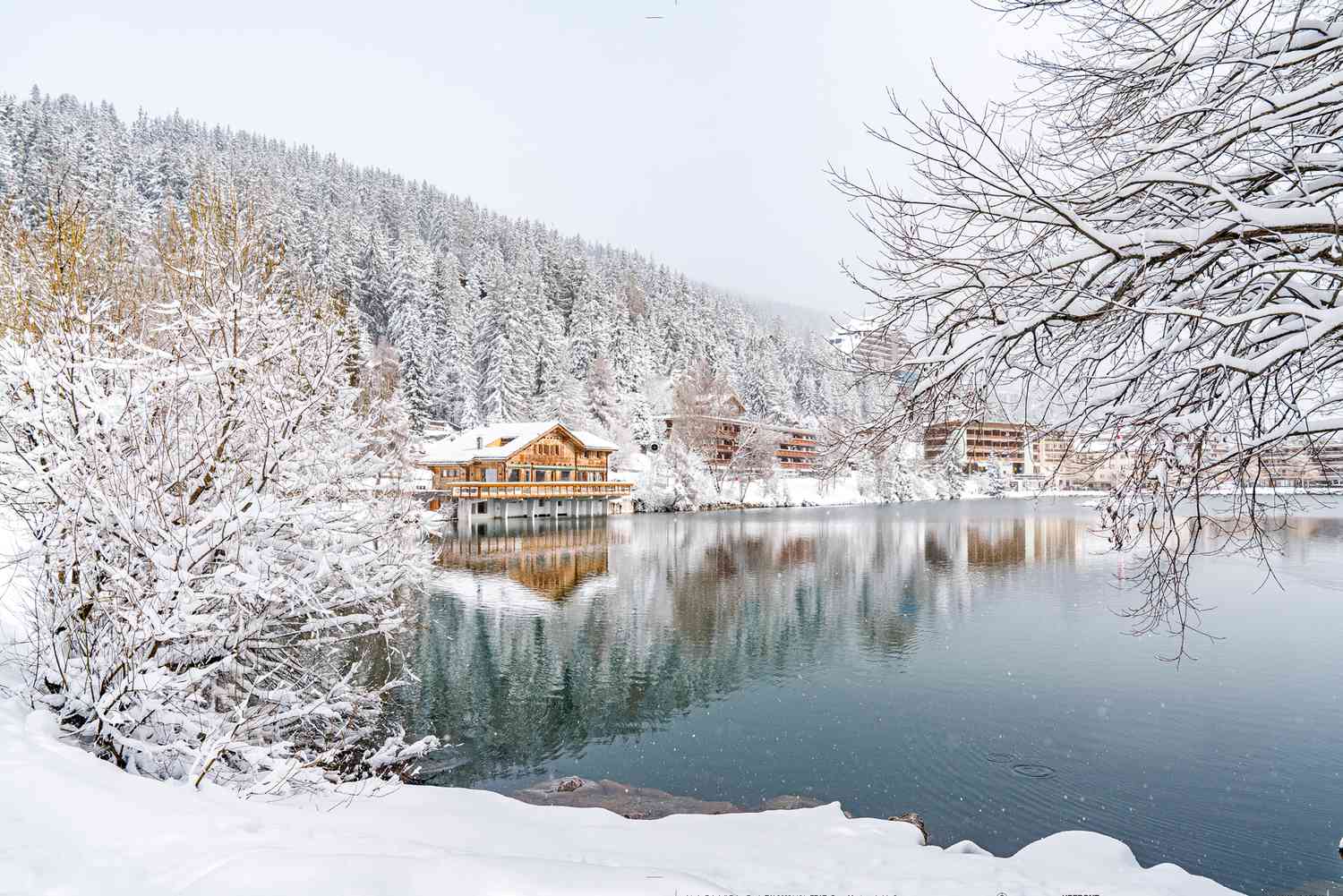 Crans Montana in Switzerland - a lake surrounded by snow covered trees.