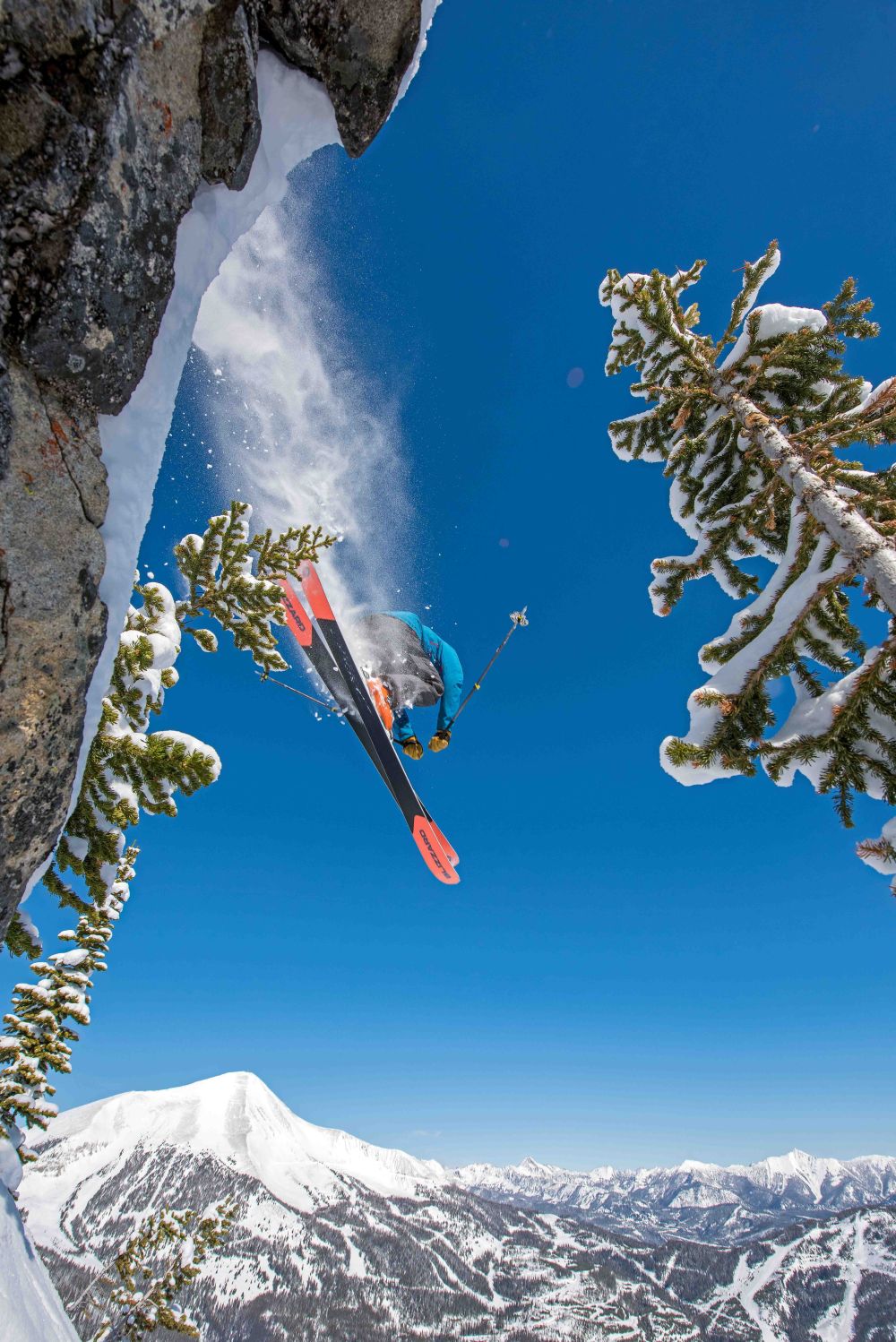 A skier is seen enjoying the slopes at Yellowstone Club in Big Sky Montana USA. This winter sports scene also showcases a snowboarder and a distant snowmobile amidst the picturesque ski resort.