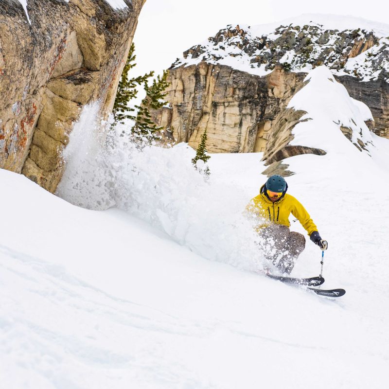 A skier and snowboarder making their way down snow-covered slopes at Yellowstone Club a renowned ski resort in Big Sky Montana showcasing a quintessential winter sports scene.