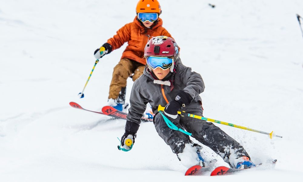 A skier and a child learning to ski at Yellowstone Club a winter sports center in Big Sky Montana USA. They appear to be part of a family enjoying the snowy scenery.