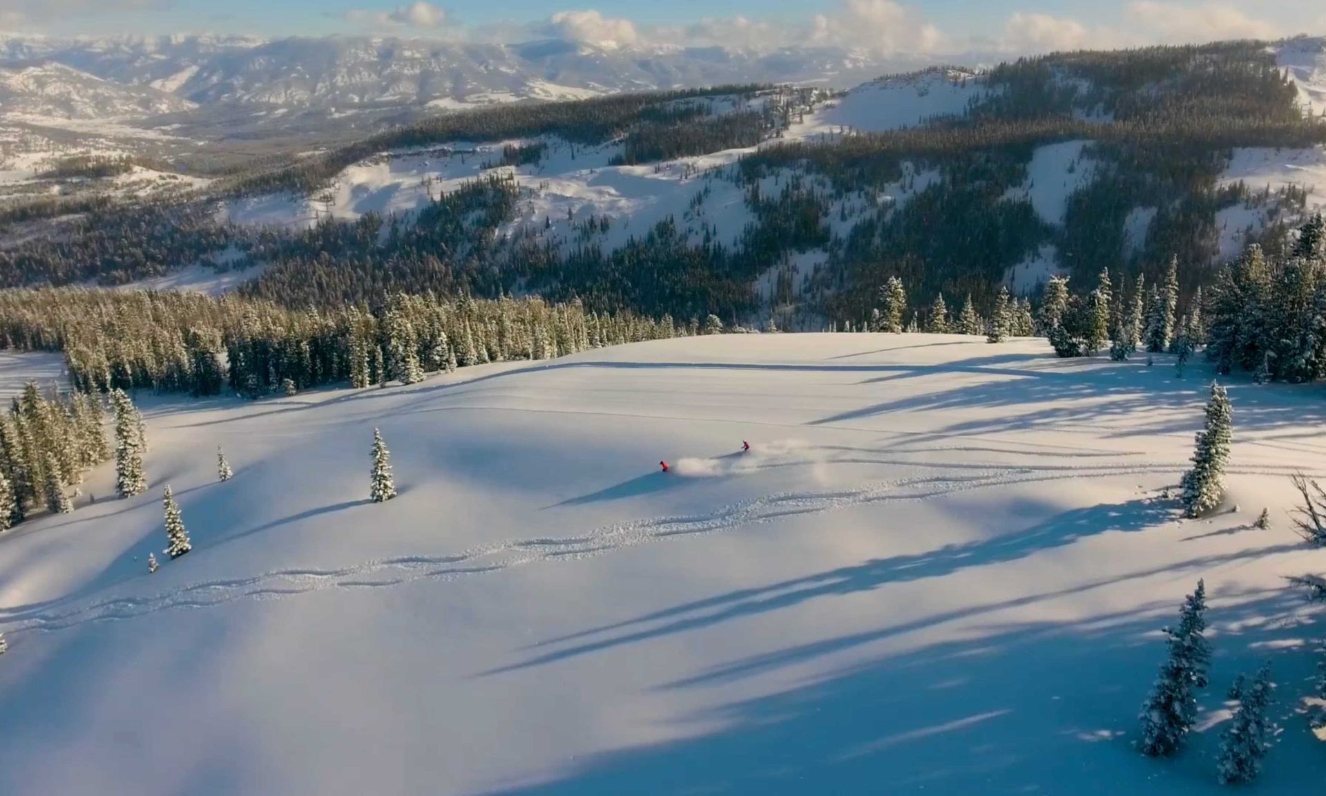 A skier glides gracefully down the slopes of Yellowstone Club in Big Sky Montana surrounded by a stunning winter scenery. The ski resort complete with ski lifts forms an inviting backdrop for winter sports.