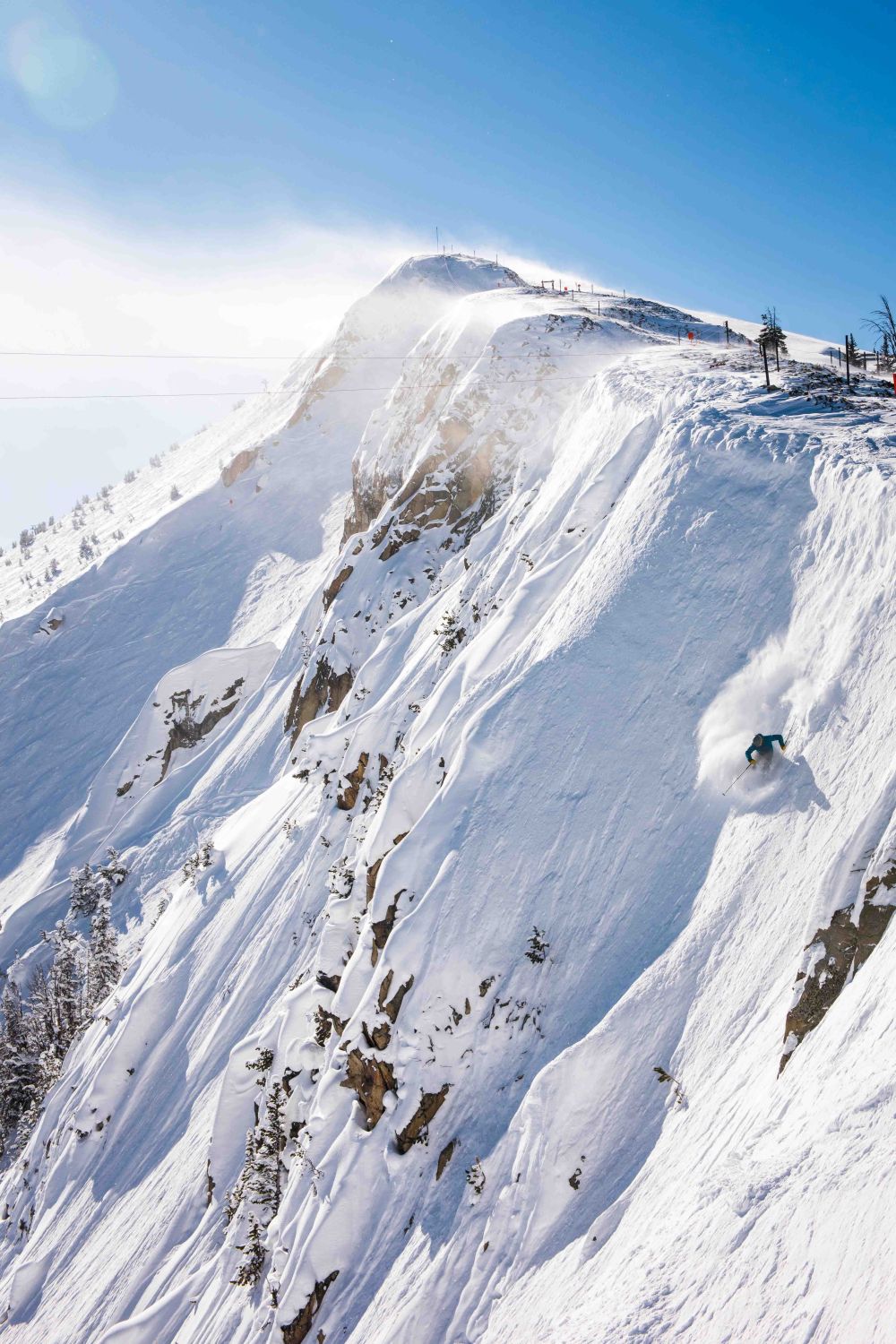 A dynamic winter scene unfolds at Yellowstone Club in Big Sky Montana. A skier is seen tackling the mountain's snow-covered slopes amidst a picturesque backdrop of a ski resort.