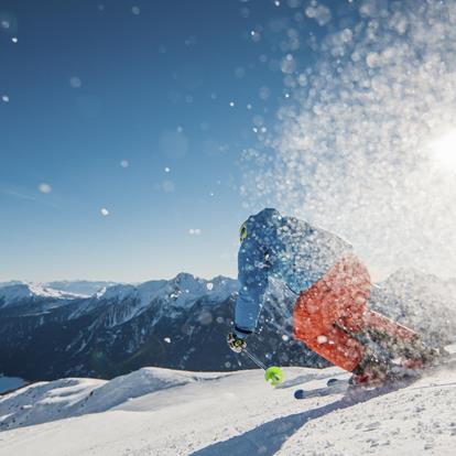 A skier and a snowboarder enjoying their winter sports activities at Schwemmalm ski resort in South Tyrol, Italy, with a charming challet nestled amidst the snowy landscape.