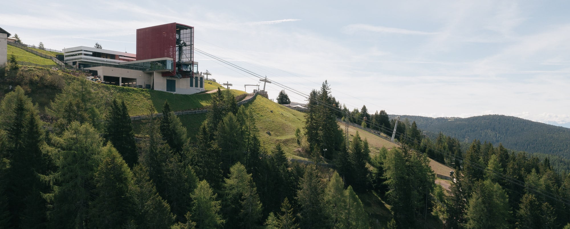 Meran 2000 in Italy: a red building on top of a green hill.