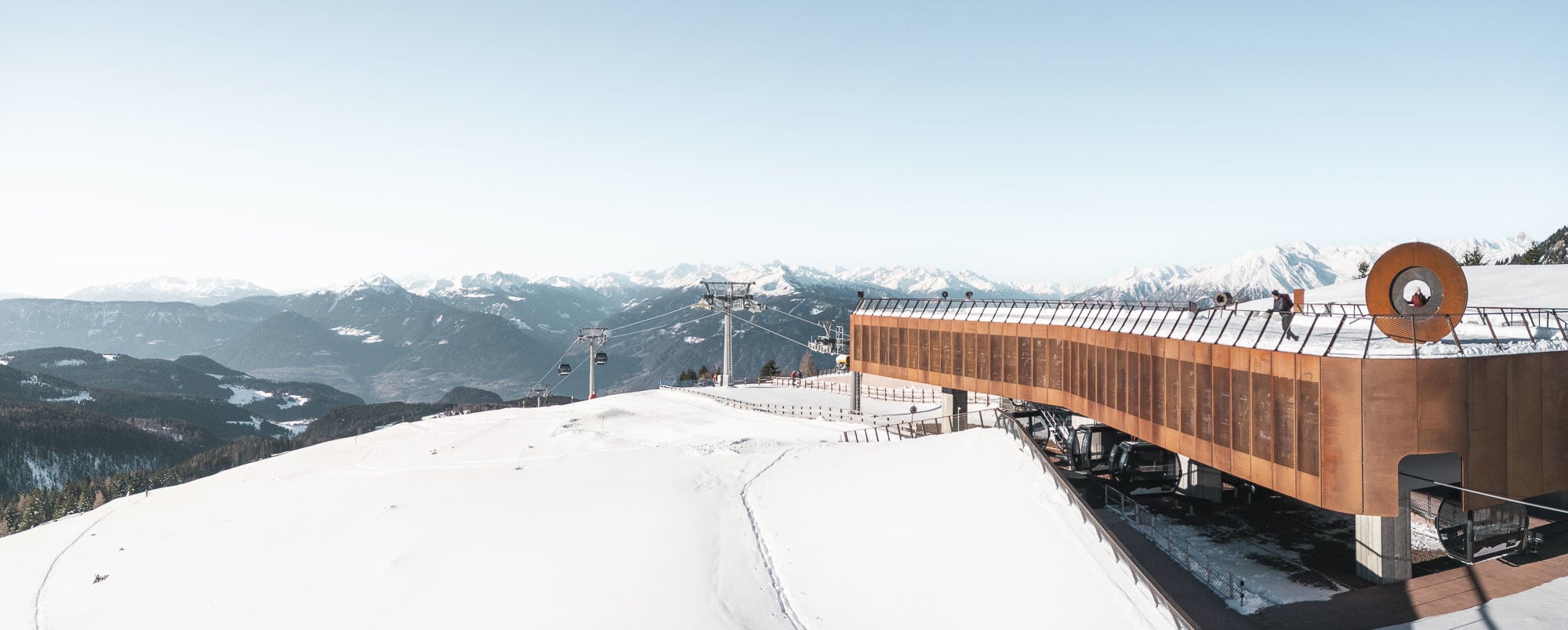 View of the picturesque Meran 2000 ski resort in South Tyrol Italy showcasing a vibrant winter sports scene with skiers on the slope a functional ski lift and a cozy mountain hut in the distance.